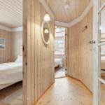 Bedroom with wooden walls, bed, and window. Hallway with mirror and door to other rooms.