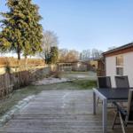 Deck with table and chairs, view of garden and house.
