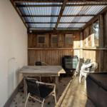 Covered outdoor area with table, chairs, and wooden wall.