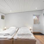 Two sleeping areas with white bedding, wooden floor, and white walls.