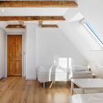 Bedroom with sloped ceiling, wooden beams, skylight, and two beds.