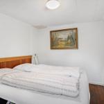 A bedroom with bed, wall painting, and radiator.