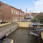 Terrace with table and chairs, view of brick building and street.