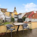 Terrace with table and chairs, view of roofs and tower.