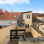 Terrace with view of yellow buildings and red roofs under blue sky.