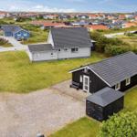 Schwarzes Ferienhaus mit Garten und Garage in einer ruhigen Wohngegend.
