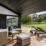Deck with seating and loungers. View of green field and trees.