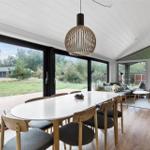 Dining area with table and chairs, large windows, and living area with sofa.