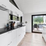 Kitchen with white cabinets, black countertop, and view to terrace with garden.