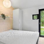 Bedroom with bed, wardrobe, and wooden wall. Door leads to outdoor terrace.