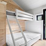 Room with bunk bed, wooden wall, and window to outdoor terrace.