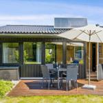 House with terrace, table, chairs, and umbrella. Solar panel on roof.