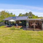 A house with a terrace and garden. On the terrace, there is a table with chairs and an umbrella.