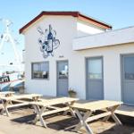 Apartment with outdoor area, wooden tables, and view of boat.