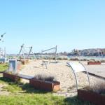 Sandy area with playground equipment and sculpture by water