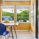 Dining room with wooden table and blue chairs, view of terrace with umbrella.