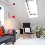 Living room with sofa, armchair, plant, and windows. White walls and ceiling.