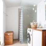 Bathroom with washing machine, sink, and shower with glass partition.