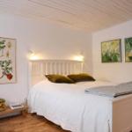 Bedroom with white bed, wooden floor, and wall art.