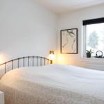 A bedroom with bed, window, and wall lamps.