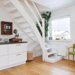 Living area with white stairs, green seating, and wooden floor.