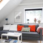 A living room with a gray sofa, orange cushions, and a white coffee table.