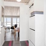 Hallway with stairs, storage, and view into living area with windows.