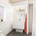 Bathroom with sink, shower, and window with flowers.