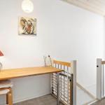 Wooden desk with chair, lamp, and flowers. Wall art and gate visible.