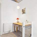 Entrance area with table, chair, and wall art. Behind the table is a staircase.