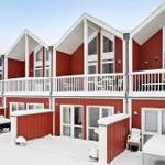 Red wooden houses with white balconies and snow on roofs and benches.