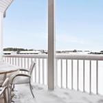Balcony with snow-covered table and chairs, white railing and red wall.