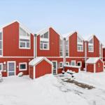 Red wooden houses with snow-covered roofs and small front yards in winter.