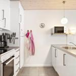 Kitchen with white cabinets, stainless steel sink, and microwave mounted on wall.