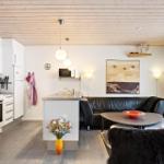 Kitchen and living area with black leather sofa, table, and wooden ceiling.