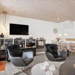 Living and dining area with TV, two chairs, and dining table. Wooden ceiling and modern lighting.