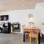 Dining area with table, chairs, and bench. TV and living area in background.