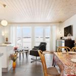Kitchen and dining area with large windows and wooden ceiling.