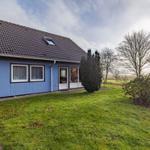 Blau gestrichenes Haus mit Dachfenster und Garten. Durchgehendes Fenster und Tür.