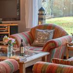 Wohnzimmer mit Sofa, Fernseher und Tisch mit Wein und Blumen.