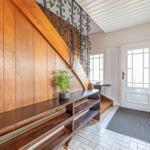 Eingangsbereich mit Holztreppe, Bänken und weißer Tür.
