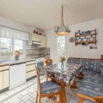 Küche mit Essbereich, Holzmöbel und gemusterten Sitzkissen.