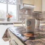 Kücheninsel mit Tischdecke, Tasse und Blumen. Hintergrund: Fenster und Spüle.