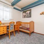 Ein Kinderzimmer mit Holz-Kinderbett, Schreibtisch und Wandbild von Schafen.