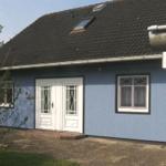 Blau gestrichenes Haus mit weißen Türen und Fenstern, Dach mit Dachfenstern.