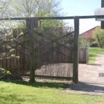 Holztor mit Bambuszaun führt zum Garten. Hinter dem Tor ist ein gepflasterter Weg.