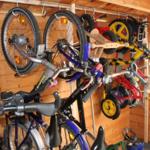 Viele Fahrräder und Kinderfahrräder hängen an Wänden in einem Holzraum.