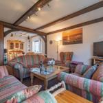 Wohnzimmer mit Sofa, Sessel und Fernseher. Holzrahmen und Glasplatte.