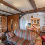 Wohn- und Essbereich mit Holzbalken, Sofa, Esstisch und Bücherregal.