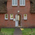 Rotes Backsteinhaus mit Strohdach und weißer Eingangstür. Hausnummer 29e. Gras und Steinstiege.